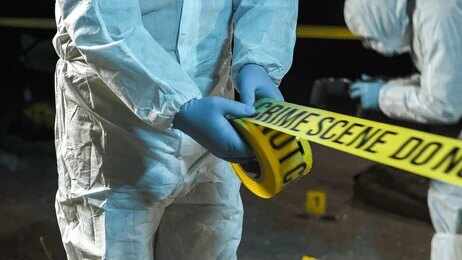 Forensic investigators in protective suits setting up crime scene tape