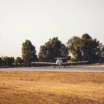 A small airplane on a runway surrounded by trees