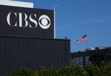 CBS logo on a building with an American flag in the background