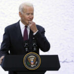 A man in a suit speaking at a podium with a presidential seal