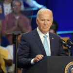 A man in a suit speaking at a podium during a public event