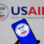 Smartphone displaying the USAID logo in front of a USAID backdrop
