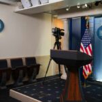 Empty White House press room with a podium and camera setup