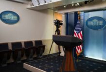 Empty White House press room with a podium and camera setup