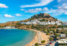 Blue Zone Smacks Big Pharma A picturesque coastal view featuring a beach, a historic castle on a hill, and a Mediterranean village