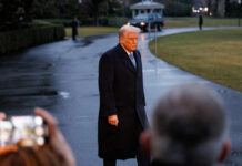 A political figure walking outdoors in formal attire during the evening