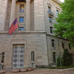 Exterior view of a government building featuring the American flag and decorative entrance