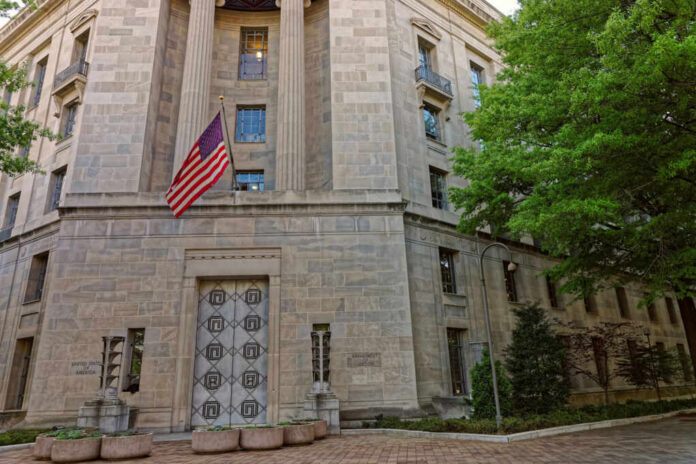 Exterior view of a government building featuring the American flag and decorative entrance