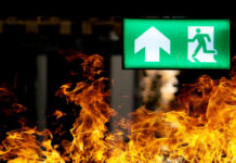 Green emergency exit sign with flames in the foreground