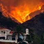 Wildfire engulfs hillside behind a suburban house