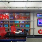 CNN newsroom set with red chairs and multiple TVs