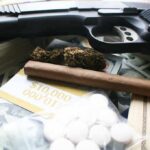 Handgun with cash, pills, and marijuana on a table