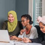 Three women collaborating at a laptop in an office