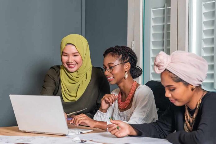 Three women collaborating at a laptop in an office
