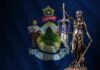 New Rape Claim Shocks Maine Power Brokers Bronze statue of Lady Justice in front of the Maine state flag