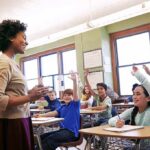 New York Schools Drop a Climate Bombshell Teacher engaging with students raising hands in a classroom