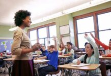 New York Schools Drop a Climate Bombshell Teacher engaging with students raising hands in a classroom