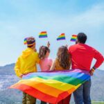 Group of friends with rainbow flags facing mountains