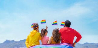 Group of friends with rainbow flags facing mountains