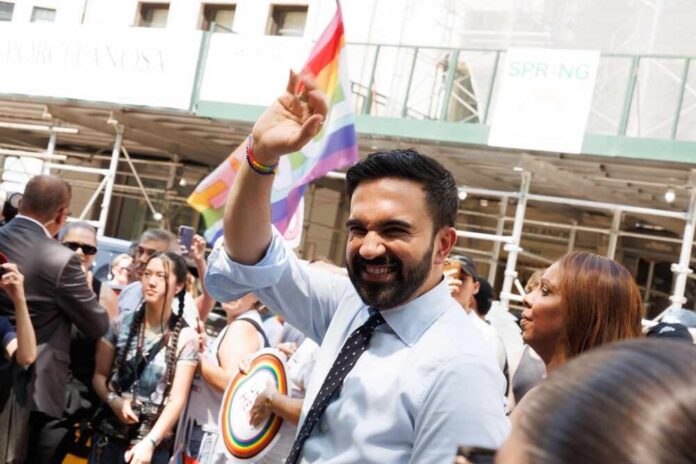 New,York,,Ny:,June,29,,2025:,Zohran,Mamdani,At,Nyc Smiling man waving at a pride parade with a rainbow flag in the background