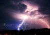 Lightning bolts illuminate storm clouds over a dark horizon
