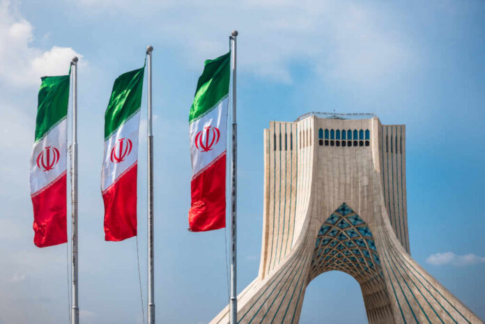 Tehran,,Iran,-,Oct,25,,2016,:,Azadi,Tower,With Three Iranian flags in front of the Azadi Tower against a blue sky