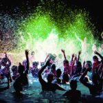 Crowd dancing in a pool under colorful lights