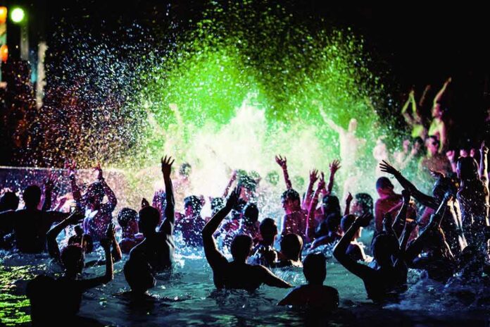 Crowd dancing in a pool under colorful lights