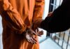 Prisoner in orange jumpsuit handcuffed by officer