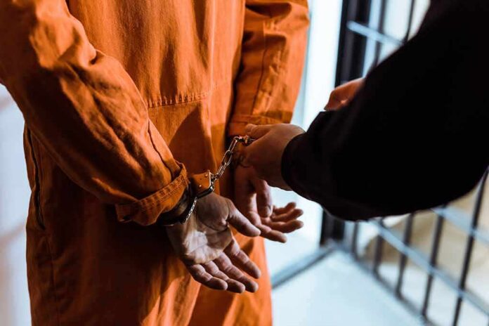 Prisoner in orange jumpsuit handcuffed by officer