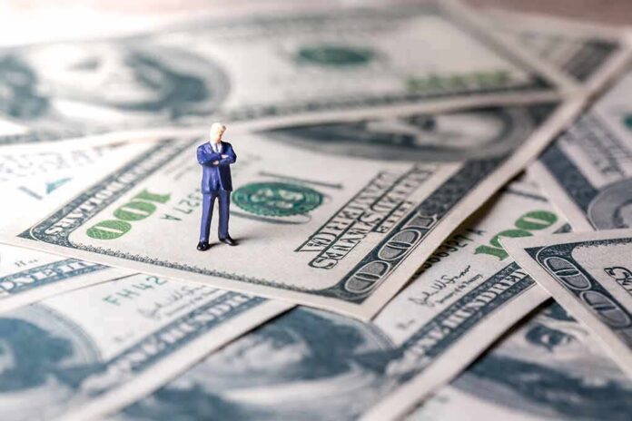 Miniature businessman standing on US dollar bills