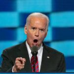 man in suit speaking passionately at a podium