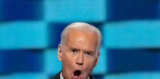 man in suit speaking passionately at a podium