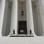 Flag-draped casket on courthouse steps between towering columns