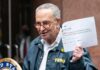 man in FEMA jacket holding a printed tweet