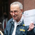 man in FEMA jacket holding a printed tweet