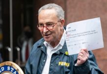 man in FEMA jacket holding a printed tweet