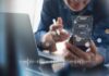 Person using smartphone with chat bubbles and laptop