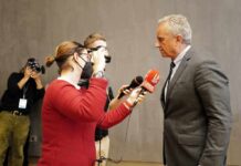man in suit being interviewed by reporters