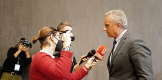 man in suit being interviewed by reporters
