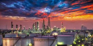 Oil refinery with storage tanks at sunset