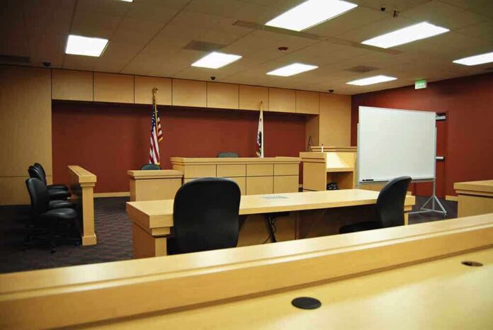 Interior view of an empty courtroom with wooden furniture and American flags