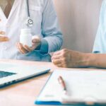 Doctor showing a pill bottle to a patient during consultation