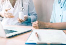 Doctor showing a pill bottle to a patient during consultation