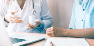 Doctor showing a pill bottle to a patient during consultation