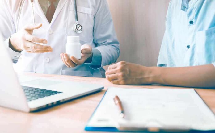 Doctor showing a pill bottle to a patient during consultation