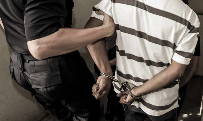 shutterstock_741919558-1 person in handcuffs escorted by an officer