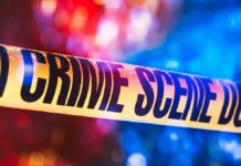 Crime scene tape with blurred emergency lights in background