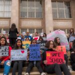 Students holding protest signs on school steps