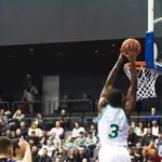 Basketball player dunks the ball in a crowded arena